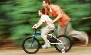 Dad and son on bike with training wheels